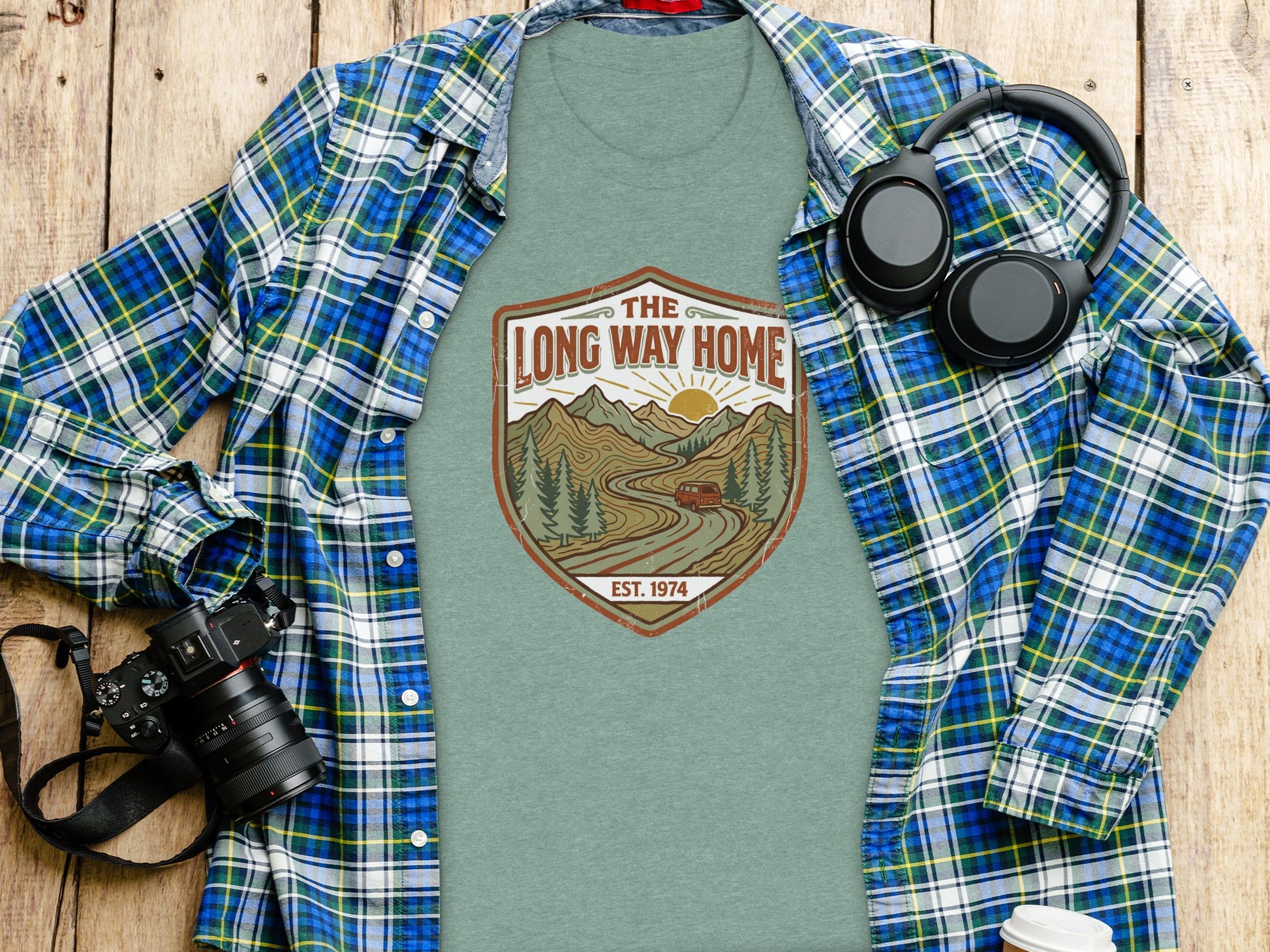 Rugged The Long Way Home | Vintage Adventure Wilderness Shirt: T-shirt with "The Long Way Home" graphic and headphones, on wooden background.