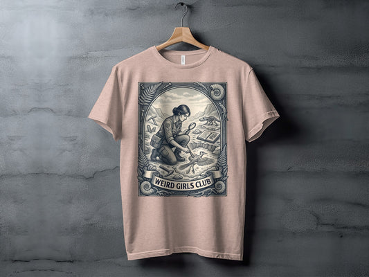 T-shirt featuring a vintage illustration of a woman examining a fossil with "Weird Girls Club" text.