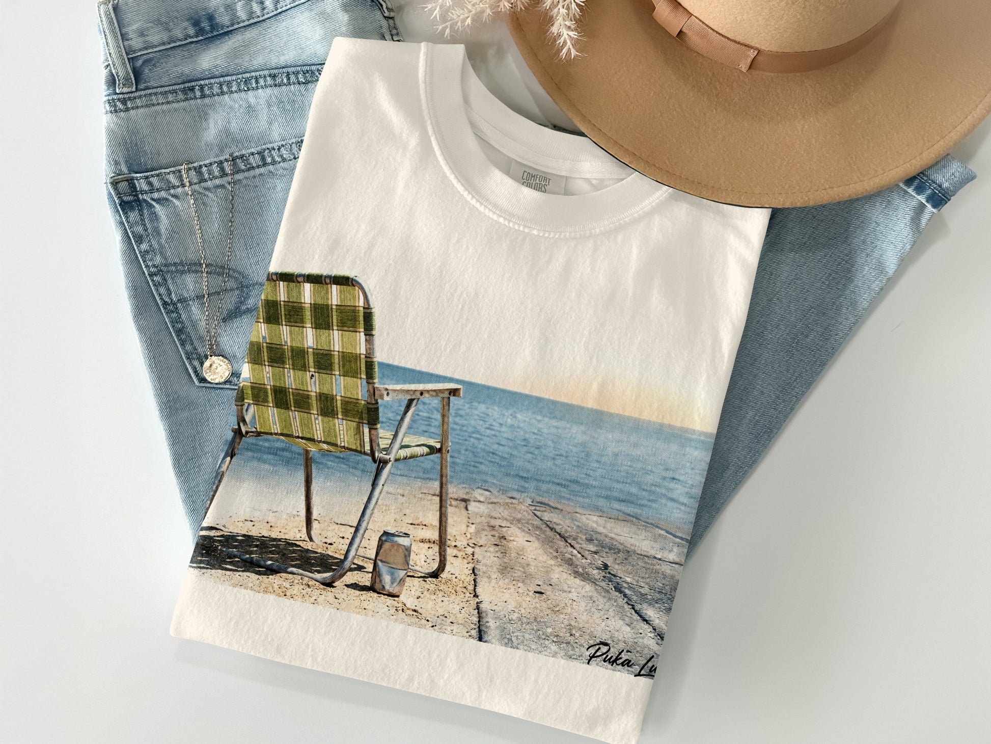 White t-shirt with graphic of a weathered beach chair overlooking the ocean.