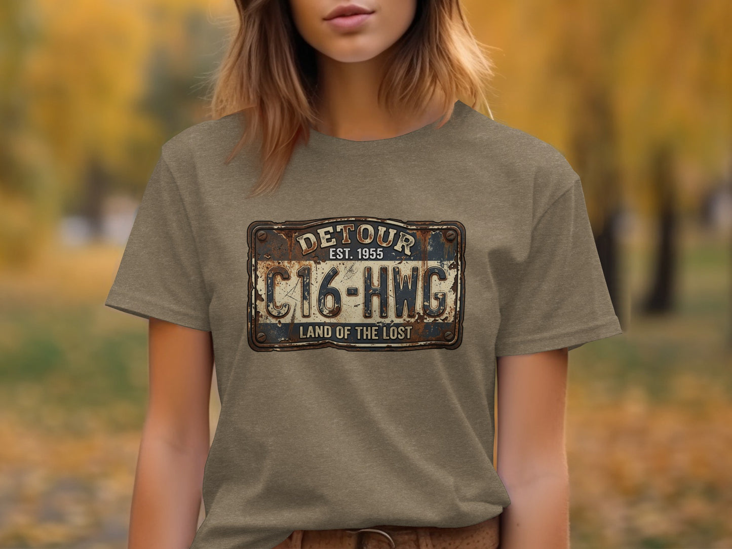 Land of the Lost Detour Plate: The Explorer's Adventure Tee: Distressed license plate design with text "DETOUR EST. 1955 C16-HWG LAND OF THE LOST".