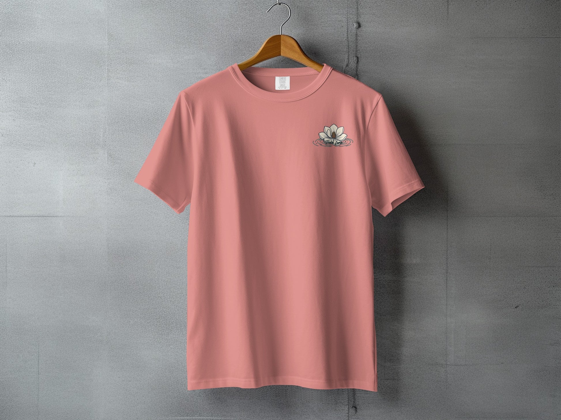 Coral t-shirt with floral logo embroidered on left chest, hanging on hanger.