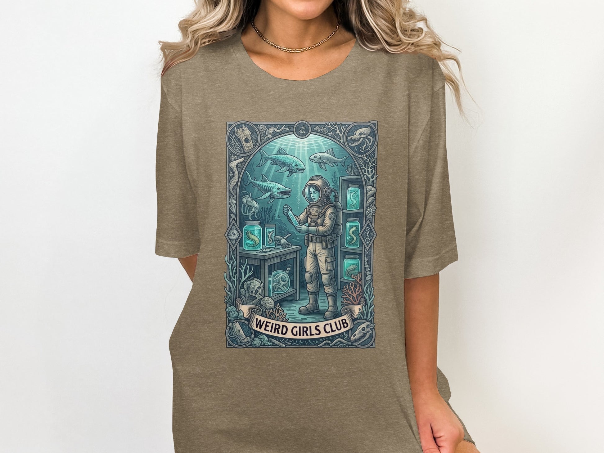 Woman wearing a graphic t-shirt with an underwater scene and a person in a diving suit.