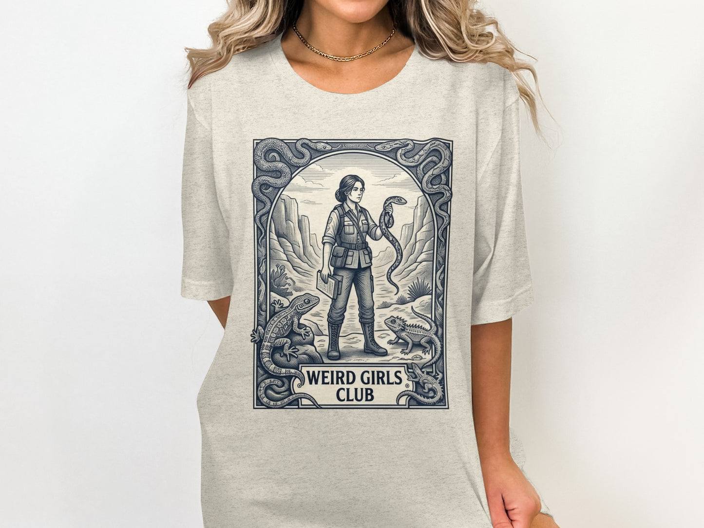 T-shirt graphic featuring a woman holding a snake in a desert scene.