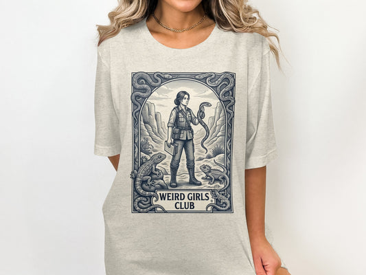 T-shirt graphic featuring a woman holding a snake in a desert scene.